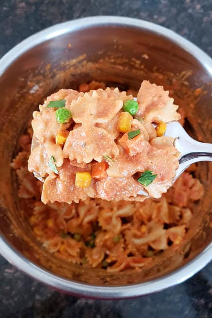 A scoop of bow tie pasta coated with creamy makhani sauce.