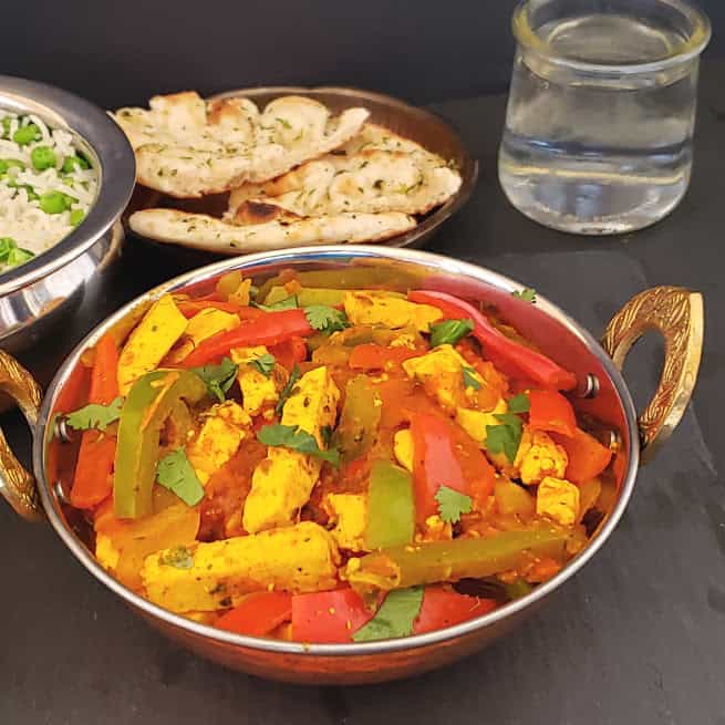 Stir fried paneer and colorful veggies in tangy Indian masala sauce sered in copper container along with peas pulao, naan and salad.