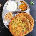 a compartment plate full of yogurt, pickle, chutney and thalippeth