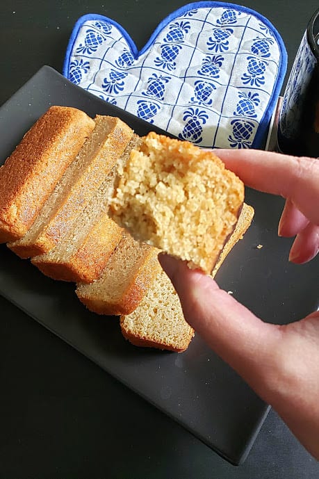 A hand holding a bite of moist and fluffy cake showing the decadent texture.