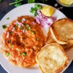 Instant Pot Pav Bhaji served with buttered pav, chopped onions, cilantro, and lemon wedges.