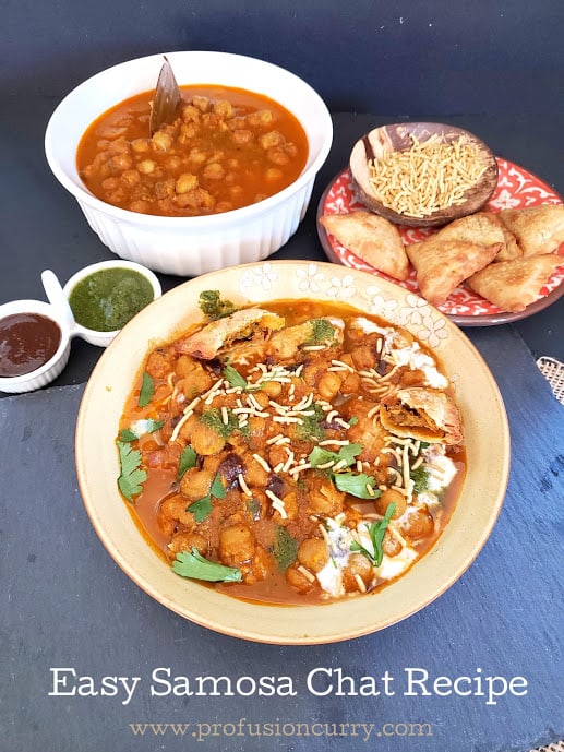 A full of serving of Indian style chat. It includes assembled plate of samosa chat along with chole curry and sev and chutney.