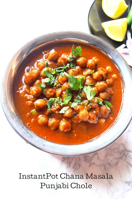 A serving platter full of chickpeas soaked in masala curry and garnished with cilantro leaves.