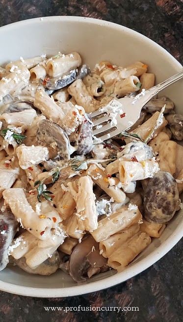 A close up shot showing creamy, velvety texture of pasta with garlic and mushrooms.