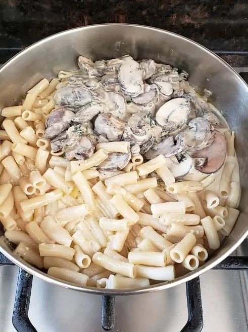 Process step photo showing the cooked pasta with creamy mushroom sauce ready to be tossed together.