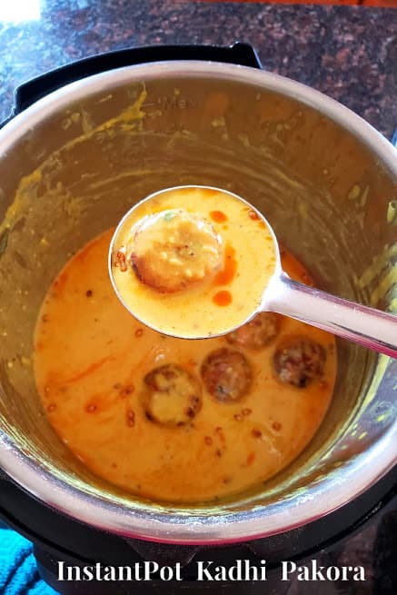 A ladle full of creamy kadhi and pan fried fritter. The curry is cooked in Instantpot.