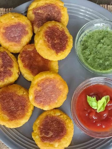 Crispy golden brown aloo tikki which is Indian spiced potato patties are served with dipping sauces.
