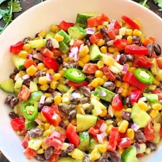 Black bean and corn salad along with avocado cilantro lime dressing served in a white salad bowl. This wholesome salad is perfect for summer lunches.