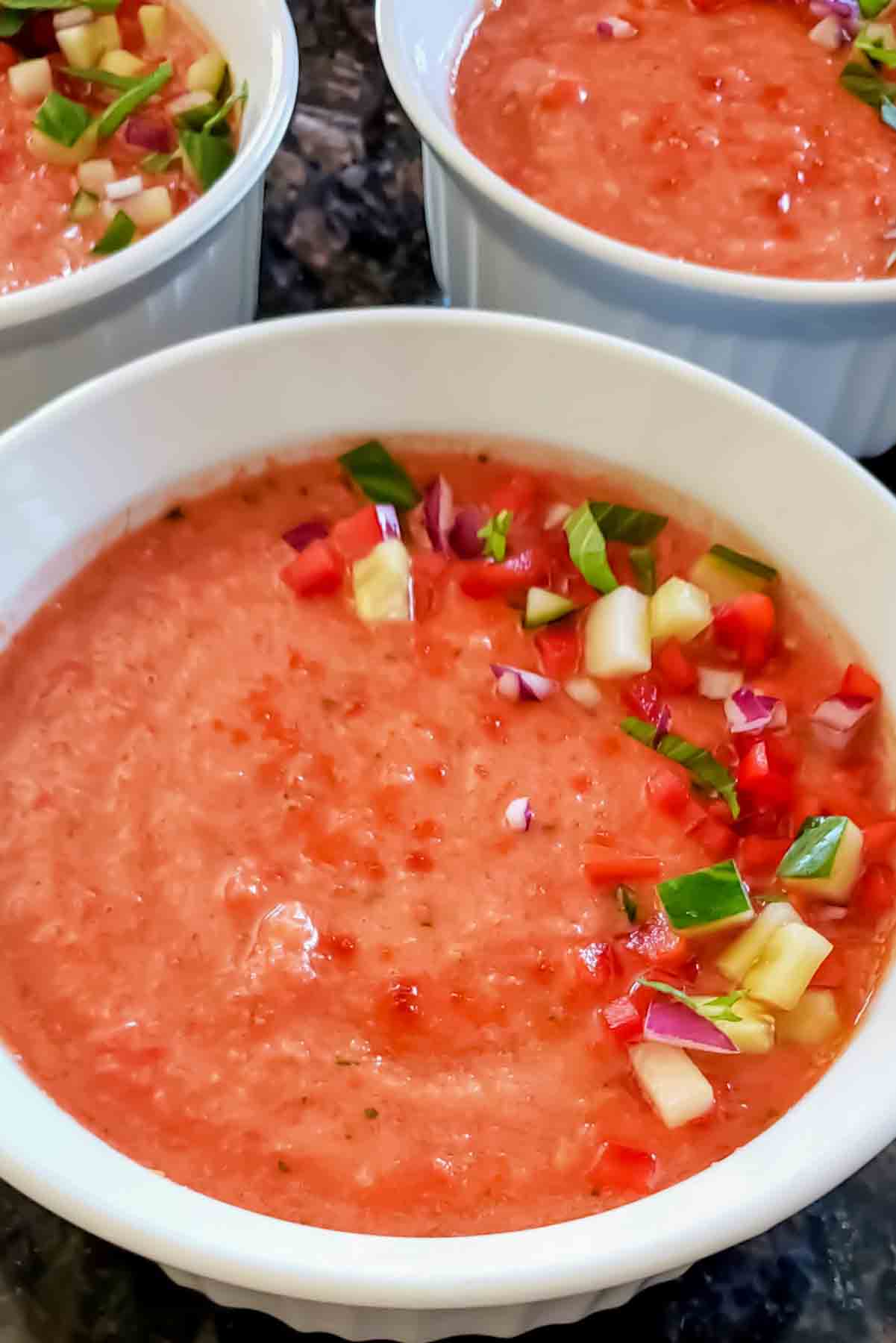 Refreshing Spanish vegan gazpacho recipe served cold with fresh vegetable toppings.