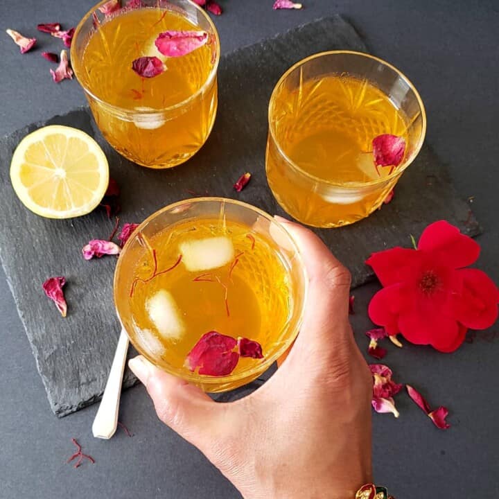 A hand holding glass of chilled saffron rose lemonade