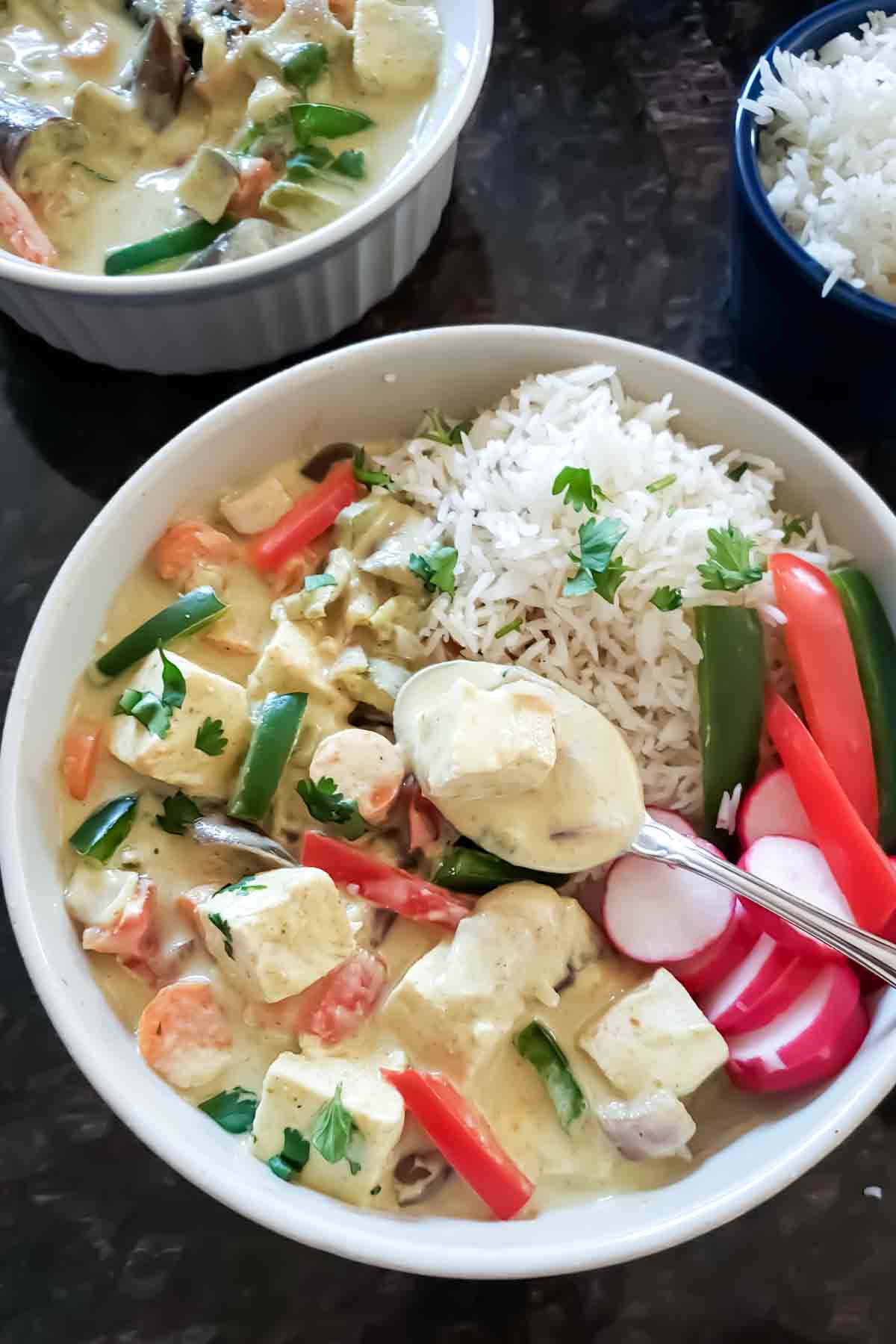 A bowl of green curry tofu with vegetables served with rice for delicious vegan and gluten-free dinner.