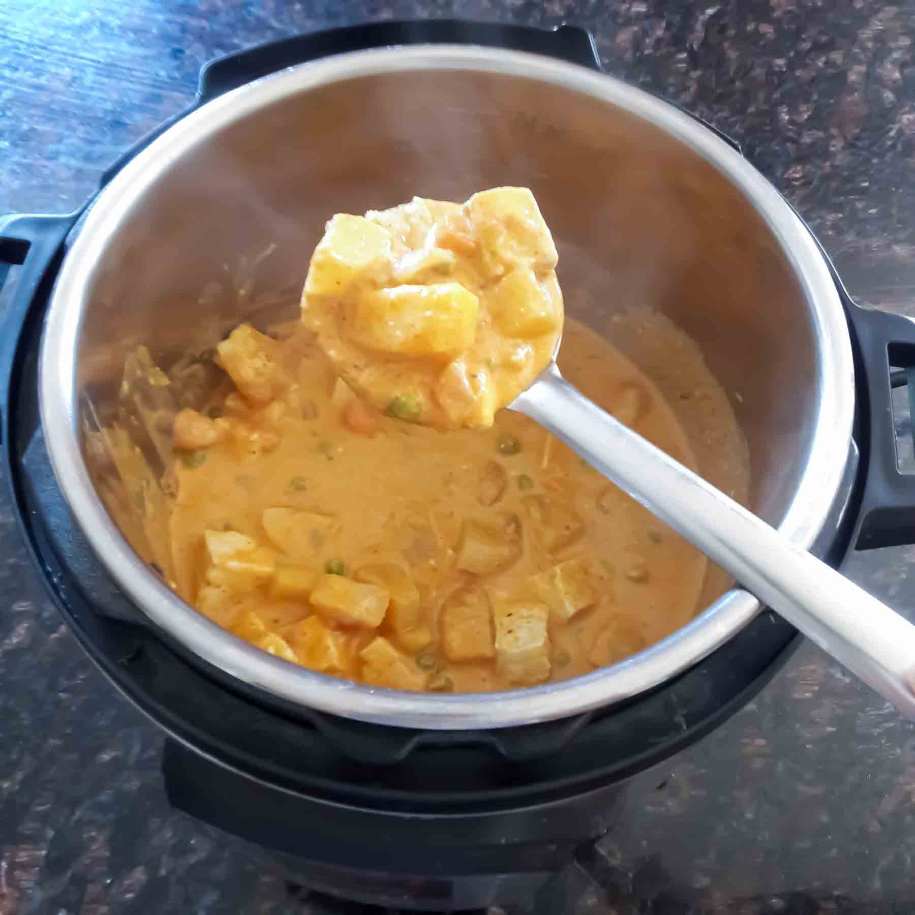 Coconut milk based Thai massman curry scooped in a ladle.