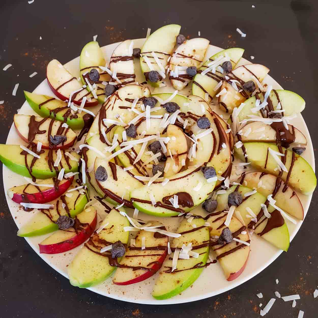 Apple nachos with peanut butter, chocolate, coconut flakes and chocolate chips for a healthy, quick, vegan and gluten-free snack/dessert.