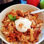 Close up image of apple crisp served with vanilla ice cream and ground cinnamon dusting