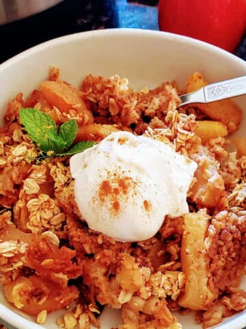Close up image of apple crisp served with vanilla ice cream and ground cinnamon dusting
