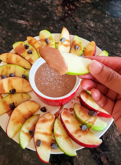 An apple slice dipped in caramel sauce.