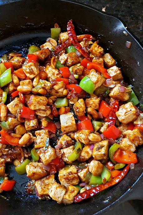 A cast iron skilett with colorful veggies and crispy tofu.