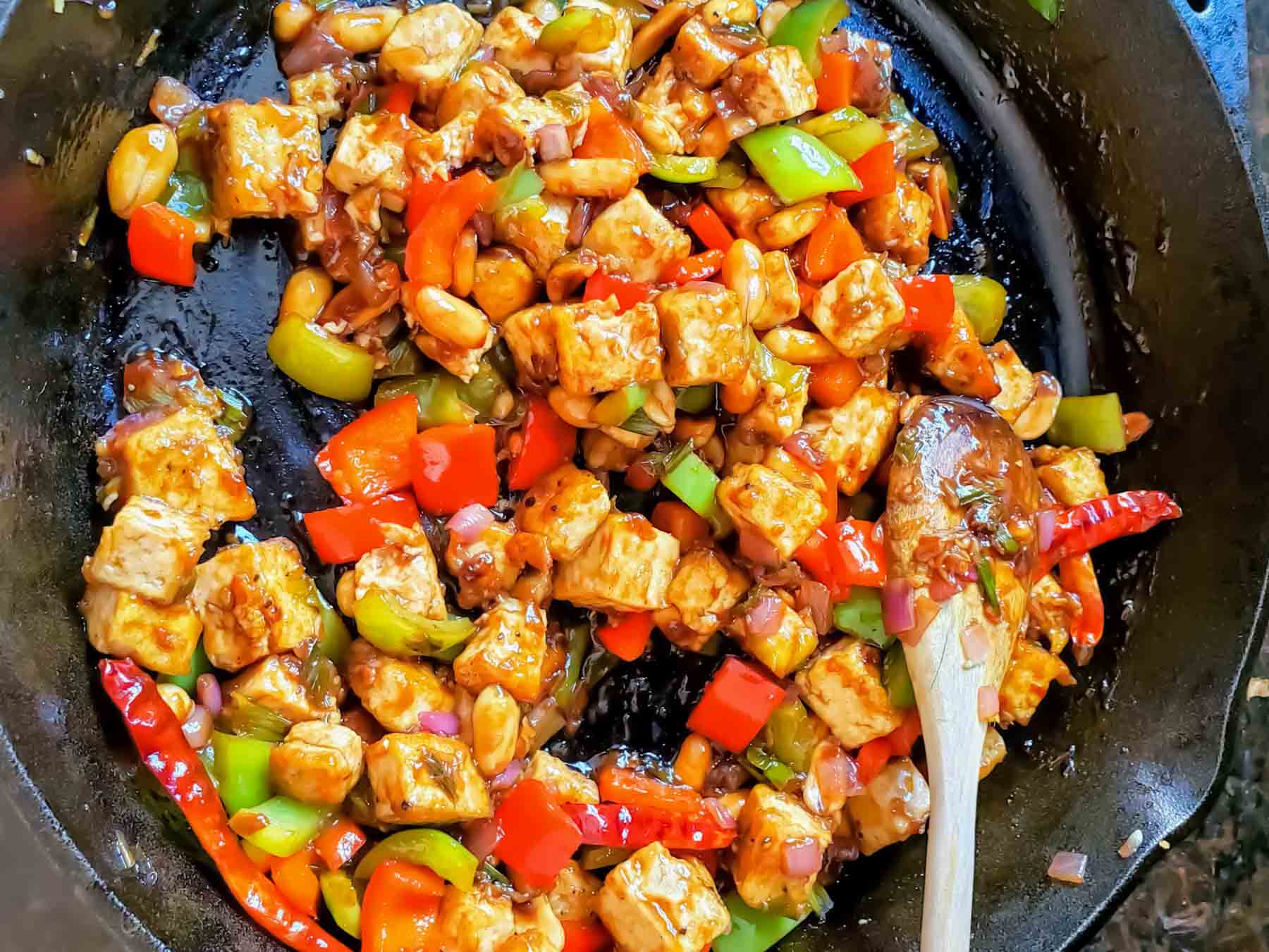 Vegan Kung Pao tofu with roasted peanuts, peppers, garlic, and ginger cooked in the wok.