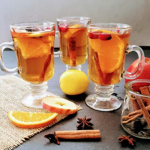 Spiced Apple cider filled glasses served with cinnamon, star anis and cloves.