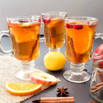 Mulled apple cider made from scratch at home served in three glasses along with garnishes.