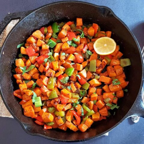 A skillet full of savory sweet potatoes and bell pepper hash.