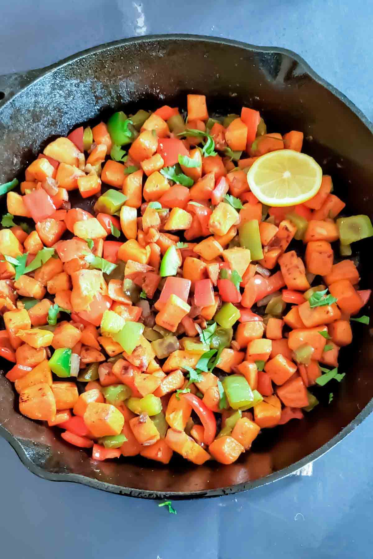 Sweet potato stir fry with bell peppers, garlic, and smoked paprika in a skillet.