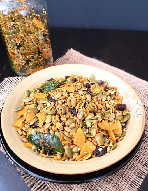 A salad plate full of seasoned seeds, raisins and coconut chips.