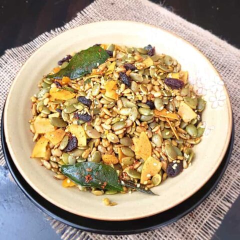 A serving plate full of Pumpkin seeds savory trail mix. It is spicy, sweet and salty mix full of superfood ingredients.