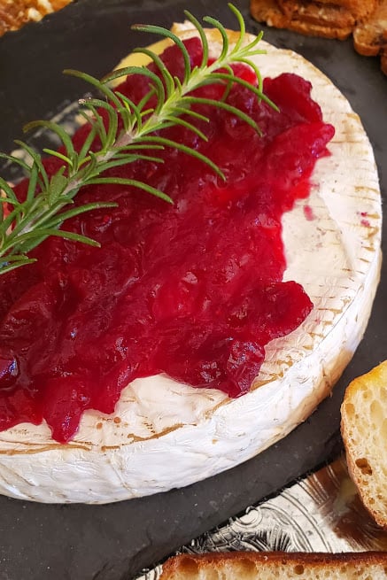 Rosemary and cranberry sauce covered brie wheel.