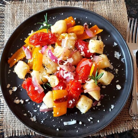 Cauliflower Gnocchi and rainbow veggies sheet pan dinner served on the dinner plate.