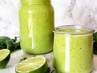 Creamy and delightful Avocado Cilantro Lime dressing poured in the glass bottle and a serving cup.
