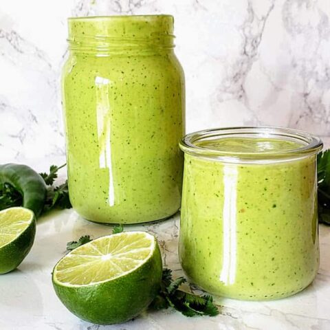 Creamy and delightful Avocado Cilantro Lime dressing poured in the glass bottle and a serving cup.