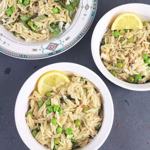 Three bowls filled with creamy lemon orzo with peas made in Instant Pot.