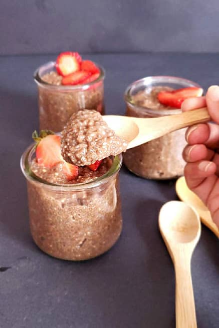 A wooden spoon full of chia seeds pudding showing thick creamy texture.