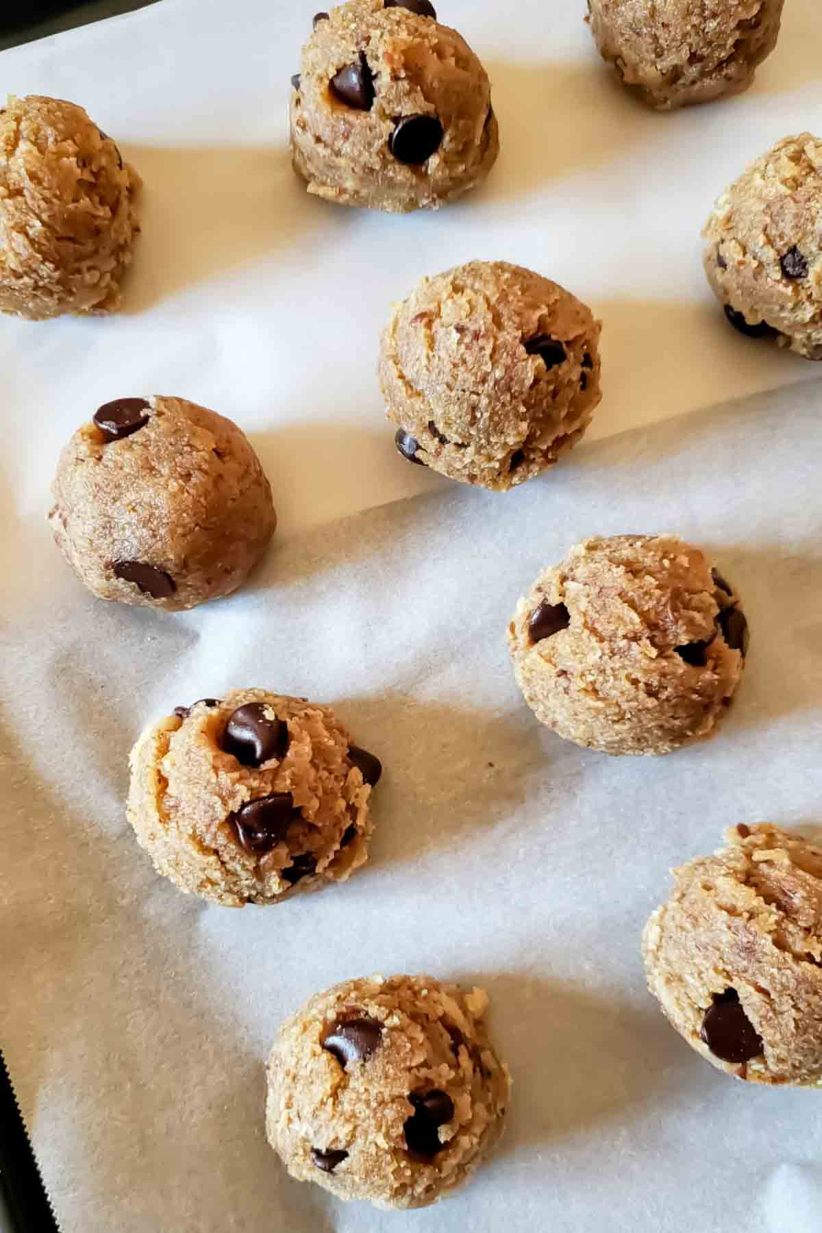 scooped edible cookie dough bites on parchment paper.
