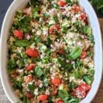 Quinoa Tabbouleh which is made with cooked quinoa, vegetables and herbs tossed in zesty lemon dressing in a bowl.