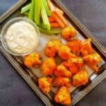 Close-up of buffalo cauliflower wings tossed in spicy sauce copycat recipe.