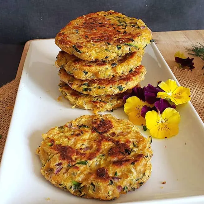 Vegan and gluten free zucchini fritters made in air fryer and served on a platter with garnishes.