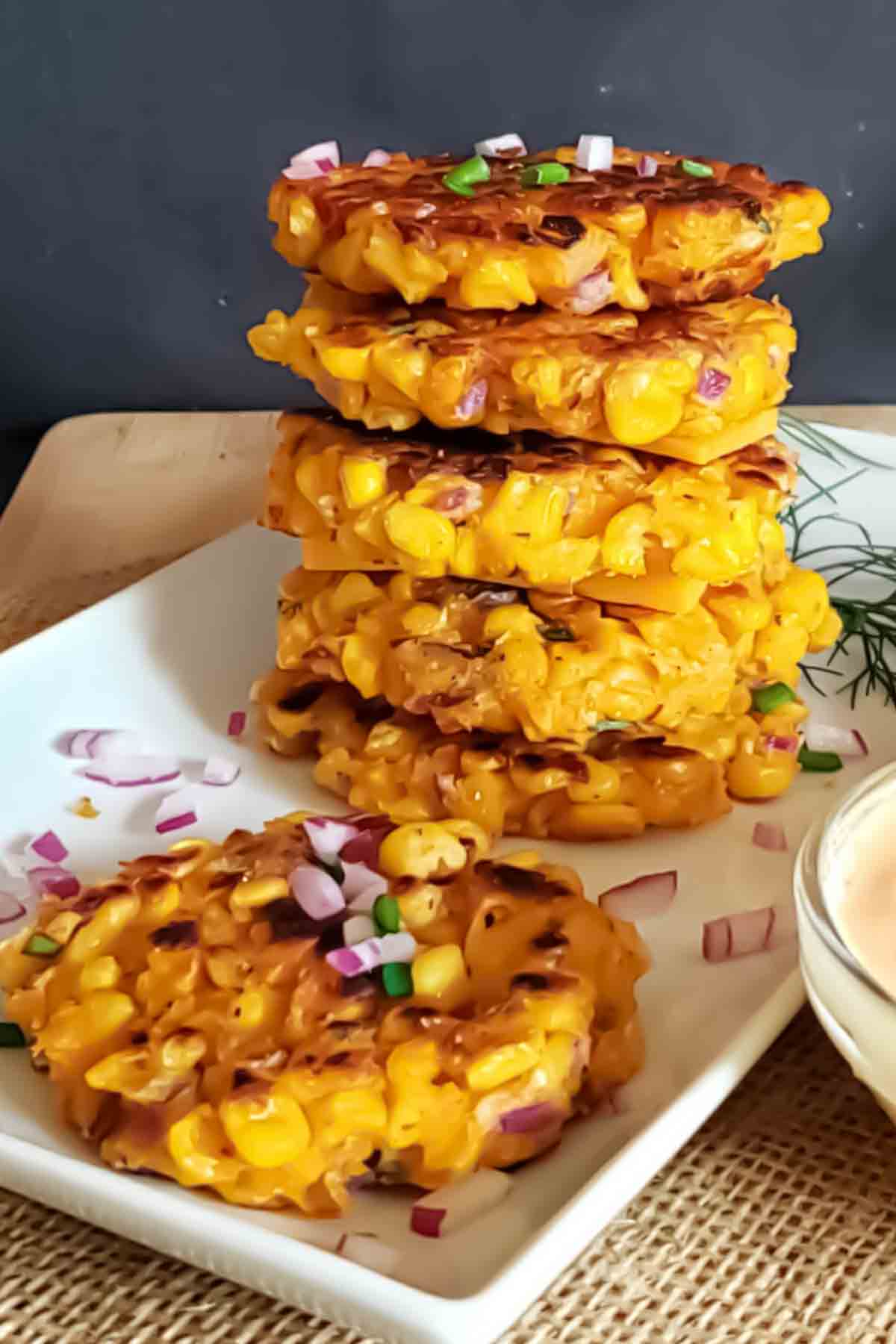 Crispy golden air fryer corn fritters on a plate with herbs.