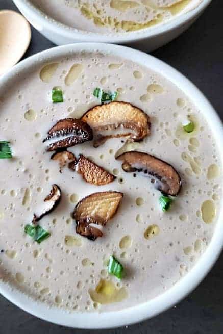 Close up showing creamy earthy soup garnished with saut&eacute;ed mushrooms. s.