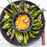 Beautifully arranged shishito peppers and corn appetizer.