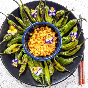 Beautifully arranged shishito peppers and corn appetizer.