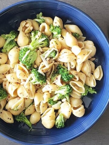 Broccoli and pine nuts studded chickpea pasta served in blue bowl.