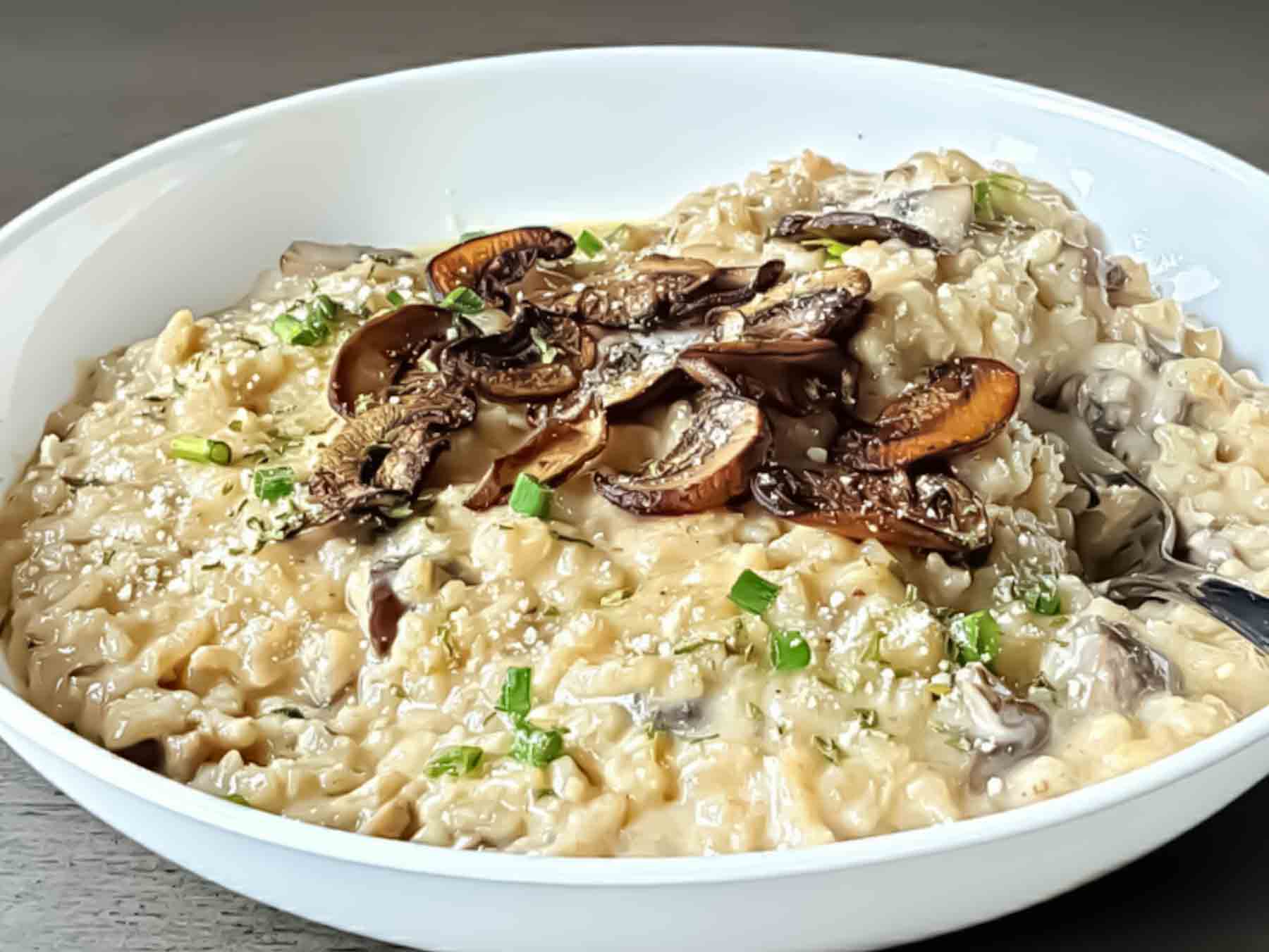 Creamy Vegetarian Mushroom Risotto served with garnishes in a bowl.