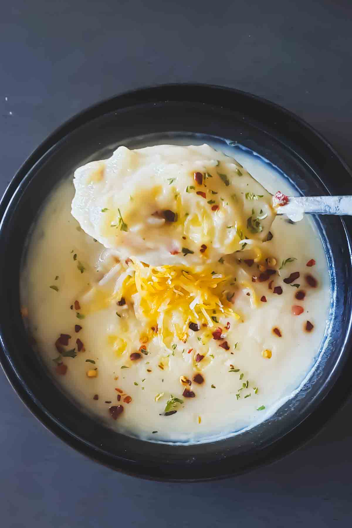 A scoop of loaded baked potato soup with granishes.