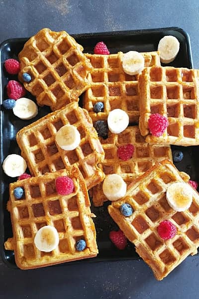 An overhead image of black baking sheet filled with pumpkin waffles.