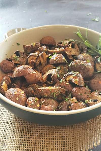 Side view of the bowl full of air roasted cremini mushrooms.
