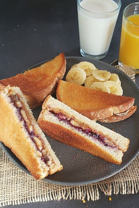 Peanut butter, jelly and banana stuffed toast sandwiches served with milk and orange juice for breakfast or brunch.