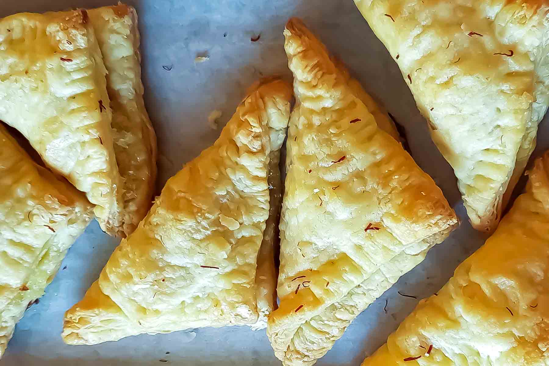 Golden flaky puff pastry triangles filled with coconut, almonds, and pistachios.