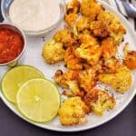 A white serving plate full of crispy air fryer curry cauliflower served as a side dish or appetizer.